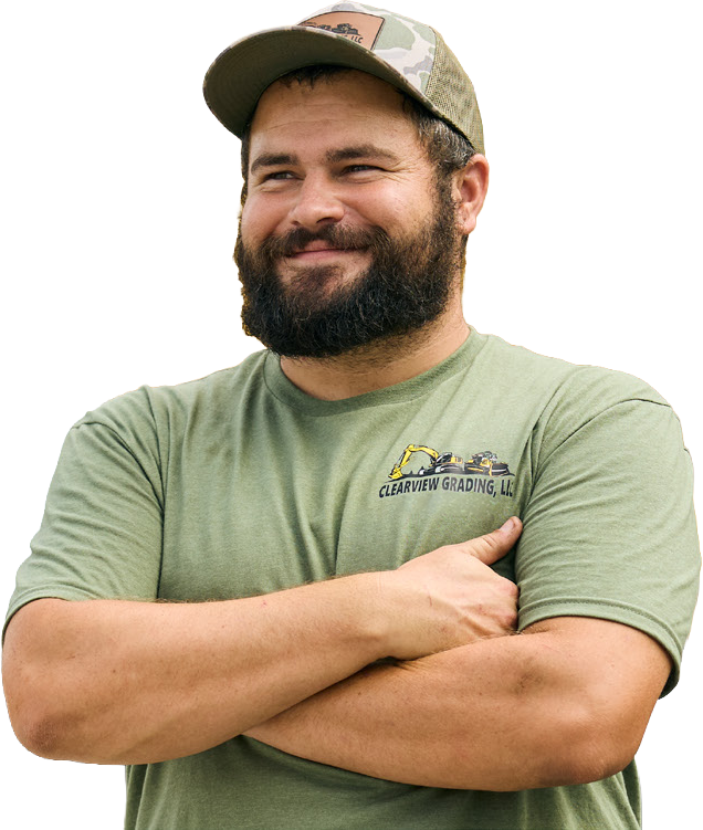 Smiling equipment operator with arms crossed in front of Cat compact machines